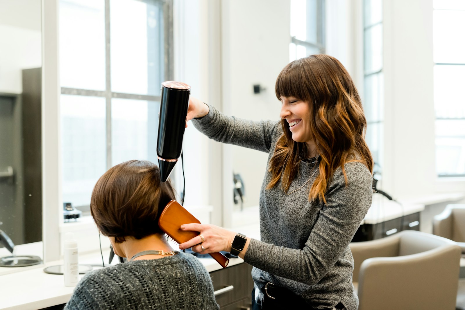 Professional hair stylist in modern luxury salon styling client hair